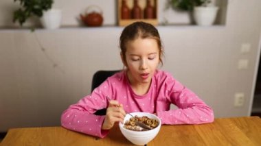 Şirin küçük kız sabah kahvaltısı için sütle mısır gevreğini iştahla yiyor ne kadar lezzetli sağlıklı yiyecekler evde kahvaltı yapan güzel çocukların ağır çekimleri..