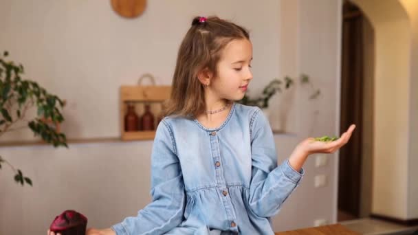 Küçük Kız Yiyecekleri Karşılaştırıyor Tatlı Pastaya Karşılık Mikro Yeşili Seçiyor — Stok video