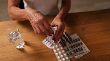 Evde elinde haplar ve bir bardak tatlı su tutan olgun bir kadın. Baş ağrısı, depresyon, ilaç takviyesi vitaminler, yatıştırıcılar, menopoz..