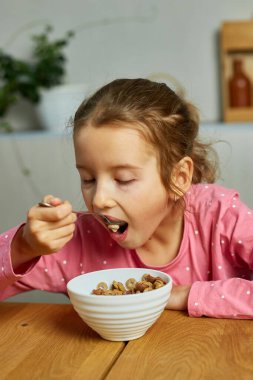 Şirin küçük kız sabah kahvaltısında kahvaltıda süt ve iştahla mısır gevreği yemekten ne kadar lezzetli sağlıklı yiyecekler evde kahvaltı yapan güzel bir çocuğun ağır çekim....