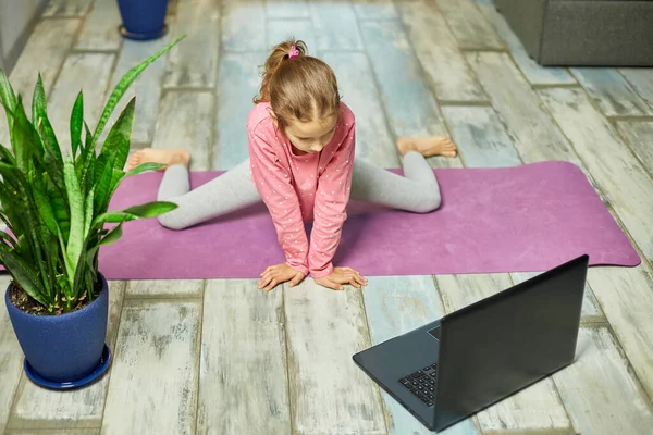 Liten Flicka Tittar Online Video Laptop Och Gör Stretching Fitnessövningar — Stockfoto