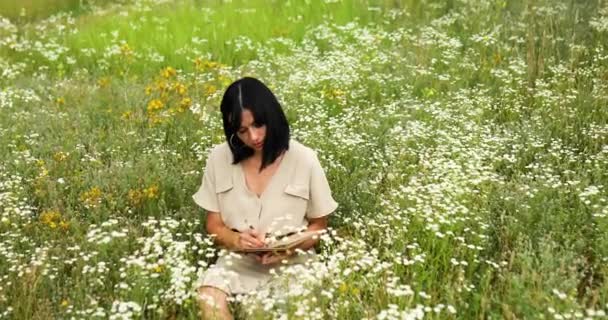 女性笔迹或绘画，笔迹写在笔记本上，花朵盛开的草地上 — 图库视频影像