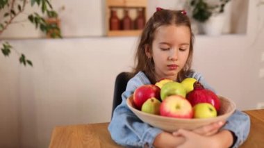 Küçük mutlu kız elinde meyve kasesi, evde sağlıklı çocuk atıştırması, evde sağlıklı yemekler, meyve ve vitaminleri sever..