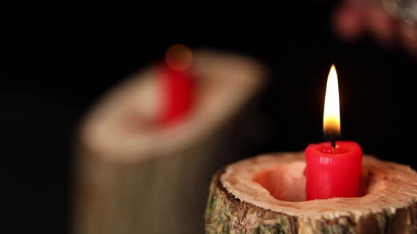 木製のキャンドルスティック黒の背景に火の上に男の手セット 2つの赤いキャンドル燃焼 — ストック動画