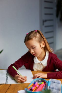 Odaklanmış liseli kız, masa başında oturup ev ödevi yapıyor, evde eğitim görüyor. Uzak öğrenim gören küçük bir kız çocuğu uzaktan eğitim alıyor ve sınavlara hazırlanıyor..