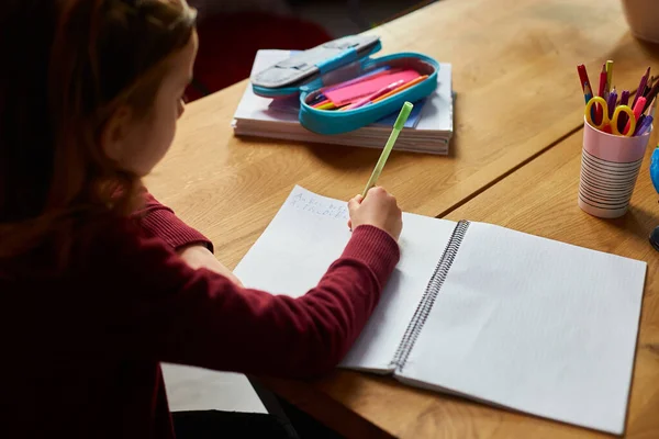 专心致志的女学生坐在课桌前写作业 在家学习 从事远程学习的小女生接受远程初等教育并准备考试 — 图库照片