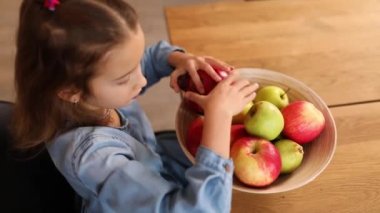 Küçük mutlu kız elinde meyve kasesi, evde sağlıklı çocuk atıştırması, evde sağlıklı yemekler, meyve ve vitaminleri sever..