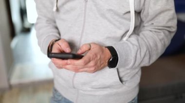 Adam akıllı telefonu iki elle yazarken tutuyor, sosyal ağdaki arkadaşlarıyla iletişimden keyif alıyor ya da telefonda oyun oynuyor, online alışveriş yapıyor, erkek kapalı alanda mobil uygulama kullanıyor.,