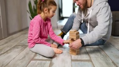 Mutlu baba ve mutlu kız, tahta kule tuğlaları ile oyun oynuyorlar, arkadaşlık kavramı ve oyun oynayarak öğreniyorlar, çocukların gelişmesi için eğlenceli eğitim oyunları.