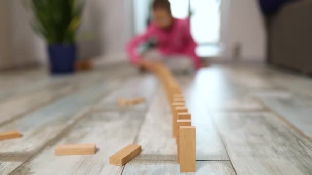 子供の開発のための活動 面白い教育ゲームを通して学ぶ 家に落ちて木製のブロックやドミノを置く小さな女の子 — ストック動画