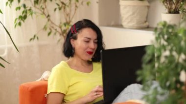 Sosyal ağda, dizüstü bilgisayarda yazarak, çalışarak, e-posta yazarak, serbest olarak evde turuncu koltuk yeşil evinde oturan bir not defteriyle mutlu ve pozitif bir kadın sohbeti..