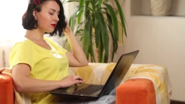 İnternette iş arama uygulaması kullanan bir kadın dizüstü bilgisayar kullanıyor, arıyor, sosyal medyayı kontrol ediyor, online alışveriş yapıyor, sipariş veriyor, yeşil ev, biyofili tasarımı.