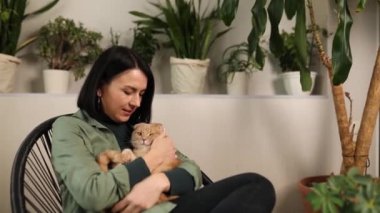Koltuğunda oturan bir kadın Sevimli kızıl bir kedi tutuyor,
