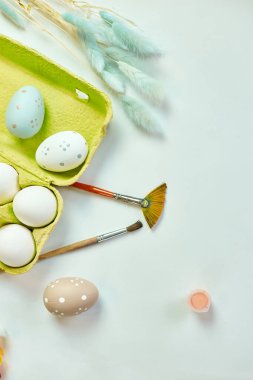 Beyaz arka planda fırçalı, boyalı ve dekoratif elementli yumurta paketleri. Uzayı kopyala, Mutlu Paskalyalar, DIY, düz yat.