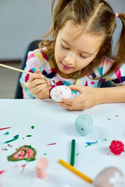 Evde fırça yumurtasıyla resim çizen mutlu küçük kız. Çocuk Paskalya için hazırlanıyor, eğleniyor ve ziyafeti kutluyor. Mutlu Paskalyalar, DIY