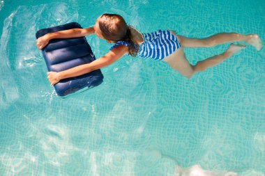 Mutlu küçük kız yüzme havuzunda eğleniyor, dalıyor ve yüzüyor, yaz tatilinde evde, tropik tatil beldesinde..