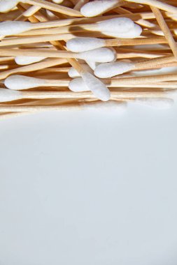 Beyaz arka planda çevre dostu pamuklar, bambu pamuk tomurcukları, tahta çubuklar, kulak temizleme için tahta çubuklar, kopyalama alanı.