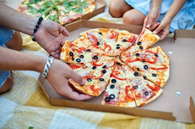 Pizza paylaşımı, açık hava kutusundan pizza alan eller, aile pikniği, akşam yemeğinde pizza yemek, fast food teslimatı..