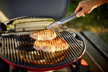 Adam gaz ızgarasında et kızarttı arka bahçede ızgara ızgara et, ızgara et, yaz aile pikniği, doğada yemek..