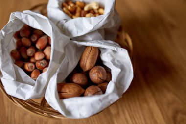Masanın üstünde, tahta arka planda bir kese kağıdının içinde çeşitli fındıklar, market konsepti, fındık teslimatı, sıfır atık yiyecek alışverişi. Boşluğu kopyala