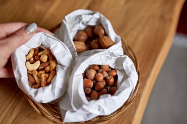 Masanın üstünde, tahta arka planda bir kese kağıdının içinde çeşitli fındıklar, market konsepti, fındık teslimatı, sıfır atık yiyecek alışverişi. Boşluğu kopyala