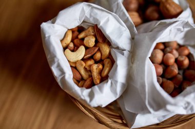 Masanın üstünde, tahta arka planda bir kese kağıdının içinde çeşitli fındıklar, market konsepti, fındık teslimatı, sıfır atık yiyecek alışverişi. Boşluğu kopyala