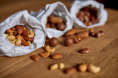 Masanın üstünde, tahta arka planda bir kese kağıdının içinde çeşitli fındıklar, market konsepti, fındık teslimatı, sıfır atık yiyecek alışverişi. Boşluğu kopyala