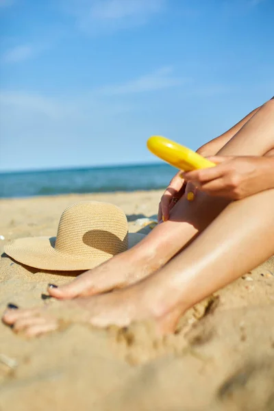 Mulher Sentada Praia Areia Colocando Protetor Solar Sua Perna Pele — Fotografia de Stock