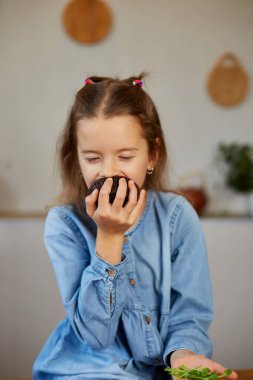 Küçük kız yiyecekleri karşılaştırıyor, mikroyeşil keki mikro-yeşil kötü alışkanlığa tercih ediyor, yetersiz beslenme kavramı.