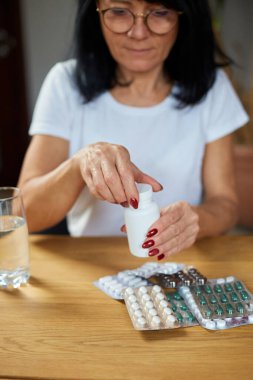 Olgun hasta kadının antibiyotik alması grip, soğuk ya da mevsimsel virüs, sağlık ve tedavi konseptinden aldığı aspirin hapları.