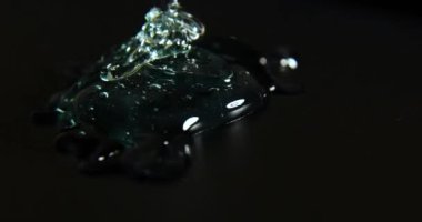 Mavi krem sıvı jel serumu siyah doku, makyaj ve kozmetik arka plan, cilt veya saç ürünü üzerine dökülür