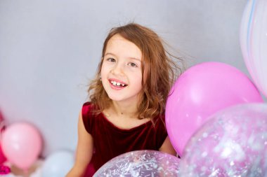 Pembe elbiseli ve şapkalı şirin küçük kız doğum günü partisinde balonlarla oynuyor, mutlu yıllar. Kutlama.