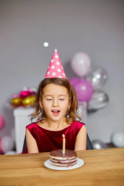 Mała Dziewczynka Sobie Urodzinowy Kapelusz Patrząc Tort Urodzinowy Dmuchanie Świec — Zdjęcie stockowe