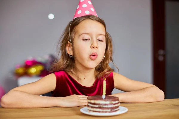 Mała Dziewczynka Sobie Urodzinowy Kapelusz Patrząc Tort Urodzinowy Dmuchanie Świec — Zdjęcie stockowe