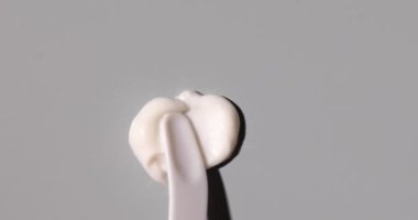 Yüz için beyaz krem örneği, organik kozmetik sıvısı, gri arka planda krem lekesi. Güzellik ürününün hareketi..