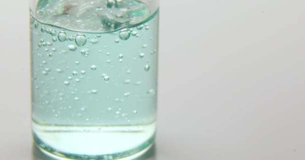 白い背景に隔離された医療用ガラス瓶に注がれた青い血清の閉じる 天然エッセンシャルオイル 化粧品 — ストック動画