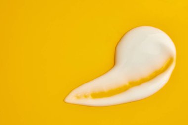 Yüz için beyaz krem örneği, organik kozmetik sıvısı, sarı arka planda krem lekesi. Güzellik ürününün hareketi..