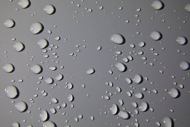 Gri arkaplanda soyut su damlaları, makro, baloncuklar kapanıyor, kozmetik nemlendirici sıvı damlaları, düz yataklar.