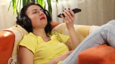 Mutlu, gülümseyen kadın kulaklıklar elinde cep telefonuyla arkadaşlarıyla ya da ailesiyle konuşurken hoparlör kullanıyor, olumlu kadın arkadaşlarıyla akıllı telefon aracılığıyla konuşmaktan hoşlanıyor, sesli sohbet ediyor.