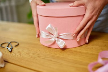 Tanımlanamayan bir kadının ellerinde pembe bir hediye paketi, hediye kutusu, Noel hediyesi ya da diğer el yapımı hediyeler mevcut kutuda fiyonk ve hediye süslemesi var.