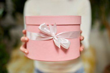 Kadın el ele tutuşması, beyaz kurdeleli pembe hediye hediye, hediye kutusu, noel hediyesi veya diğer el yapımı hediyeler, yavaş çekim