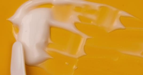 有機化粧品液体 黄色の背景にクリームスマッジの白いクリームのサンプルスミア 美容スキンケア製品の動き — ストック動画
