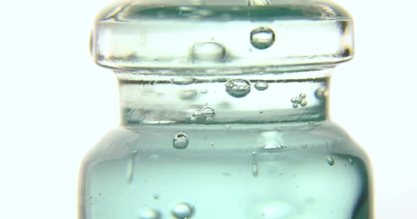 医用玻璃瓶中的蓝色泡沫血清的闭合 用白色背景隔离 天然精油 化妆品 — 图库视频影像