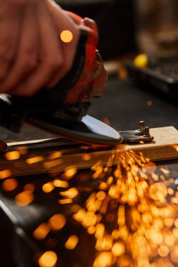 Çilingir makinesiyle çalışır, parlak kıvılcımlar saçar. Bir adam atölyede metal öğütüyor, metal işinde kıvılcım saçıyor..