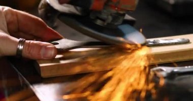Çilingir makinesiyle çalışır, parlak kıvılcımlar saçar. Bir adam atölyede metal öğütüyor, metal işinde kıvılcım saçıyor..