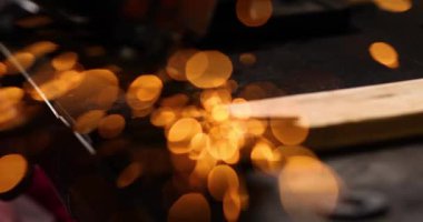Çilingir makinesiyle çalışır, parlak kıvılcımlar saçar. Bir adam atölyede metal öğütüyor, metal işinde kıvılcım saçıyor..
