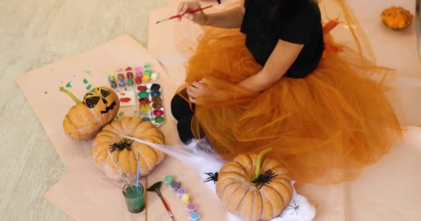 家でカボチャを飾る幸せな子供オレンジのハロウィンジャック ランタンカボチャに顔を描く小さな女の子 休日の装飾コンセプト — ストック動画
