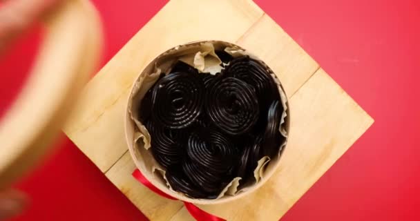 フラットレイおいしいブラックリコリスキャンディーの黒の背景に回転 キャンディー風味のリコリス トップビュー — ストック動画