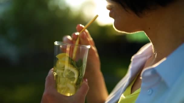 女人在后院的房子里喝夏季柑橘类柠檬水和可重复使用的金属稻草派对 有冷饮 环保的酒草 健康的生活方式 排毒水 — 图库视频影像