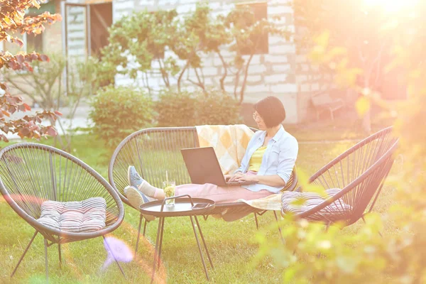 Female typing on the laptop for remote working, Freelancer woman working with laptop, checking social media, shopping online, ordering delivery at home in the backyard outdoor in the garden